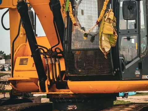 Yellow tracked excavator showing its boom and hydraulic arms