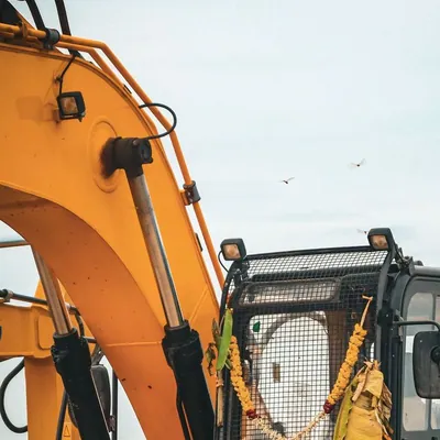 Yellow tracked excavator showing its boom and hydraulic arms